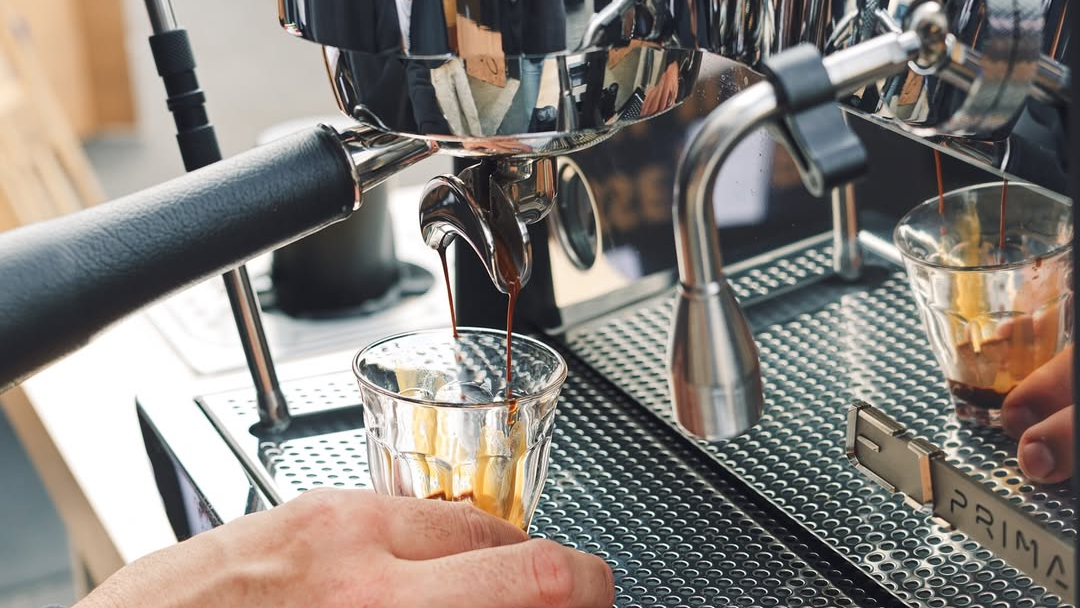 Espresso machine in action with two small glasses receiving espresso shots.