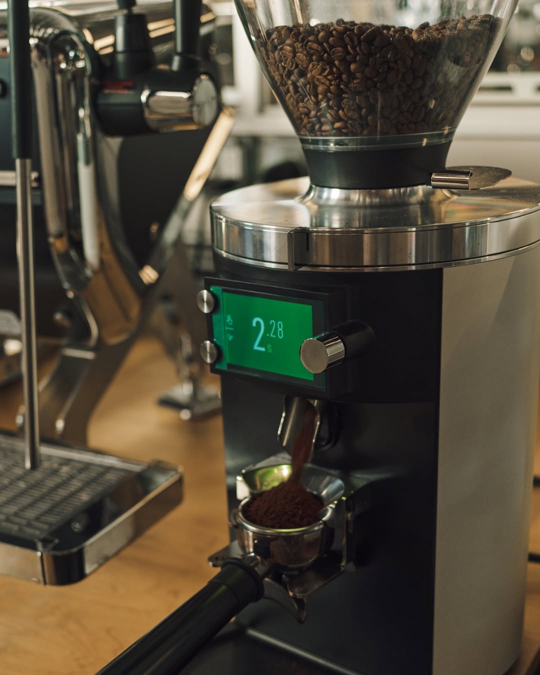 Coffee grinder with a digital display showing 2.8, filled with coffee beans.